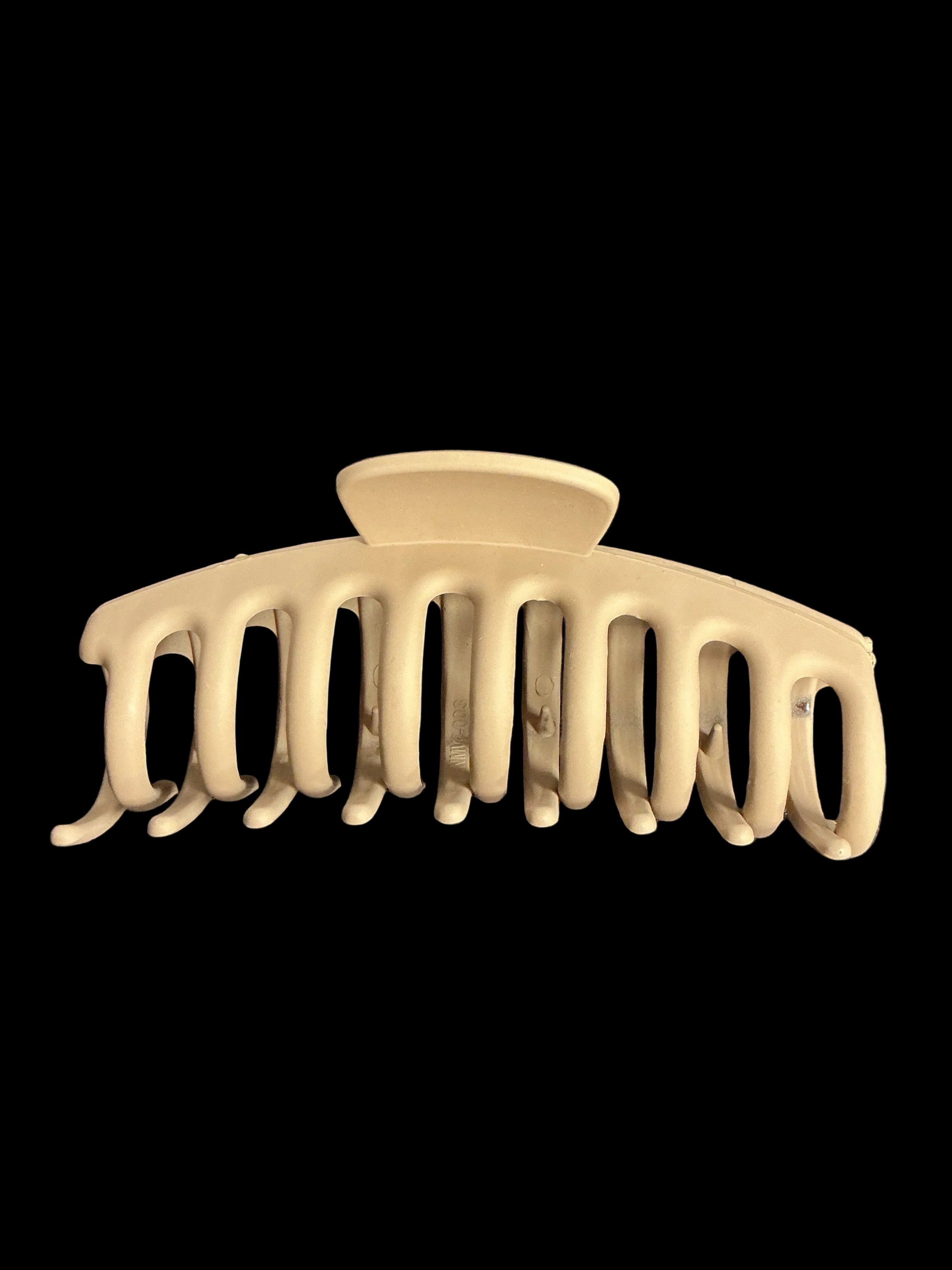 A cream-colored hair claw clip shown against a solid black background.