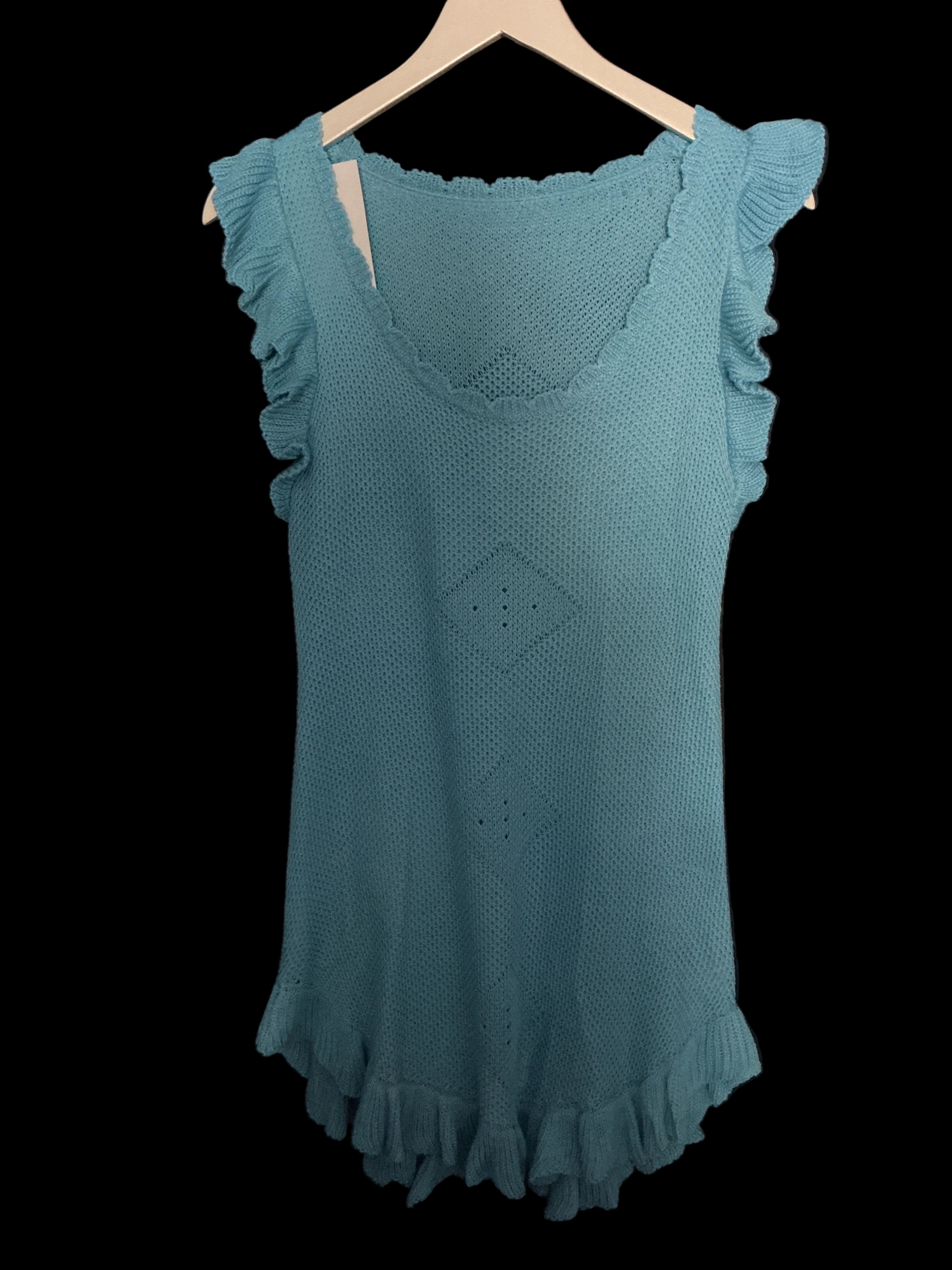 A light blue knit sleeveless top with ruffled trim, laid flat on a black fabric background and hanging from a white hanger.